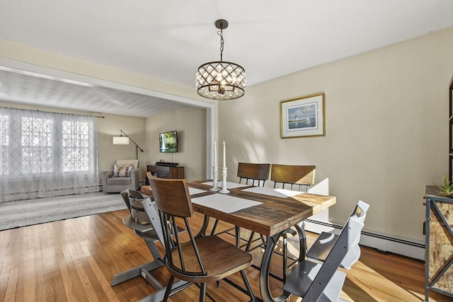 dining area featuring a baseboard radiator, hardwood / wood-style floors, and a notable chandelier