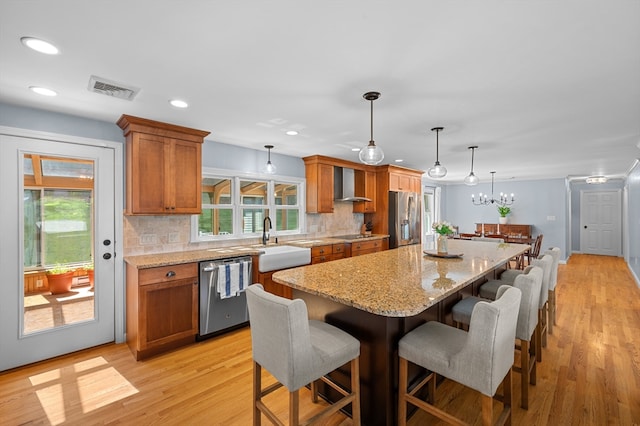 57 Hampton St, Auburn, MA 01501 - kitchen featuring appliances with stainless steel finishes, wall chimney exhaust hood, brown cabinetry, decorative backsplash, and a center island