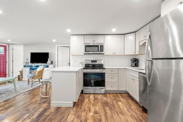 22 Janet St, Plymouth, MA 02360 - kitchen with appliances with stainless steel finishes, a peninsula, light countertops, white cabinets, and wood finished floors