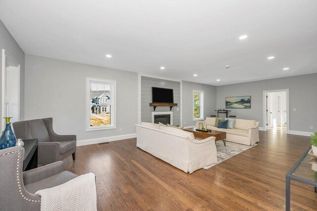 unfurnished living room featuring a large fireplace, wood-type flooring, and a wealth of natural light