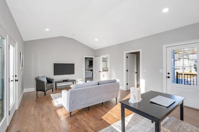 spare room featuring light wood-type flooring, vaulted ceiling, and a healthy amount of sunlight