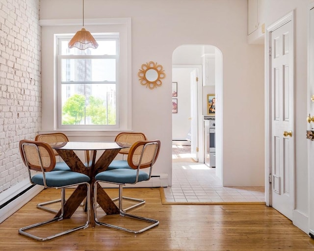 11 Revere Unit 4, Boston, MA 02114 - dining room featuring brick wall, arched walkways, healthy amount of natural light, wood finished floors, and baseboard heating