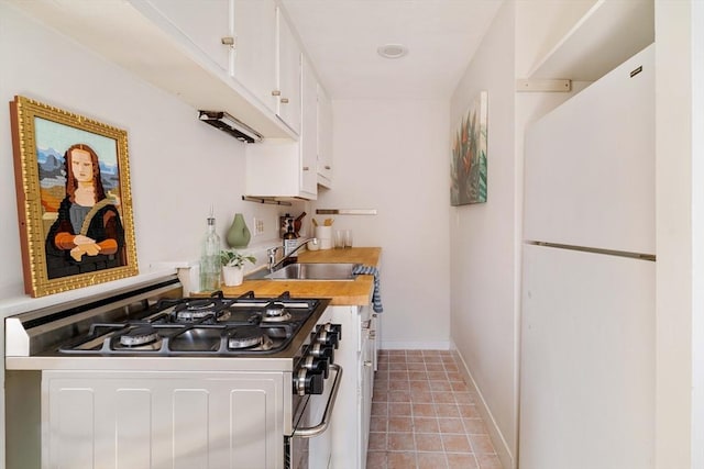 11 Revere Unit 4, Boston, MA 02114 - kitchen featuring stainless steel range with gas cooktop, freestanding refrigerator, a sink, white cabinets, and light countertops