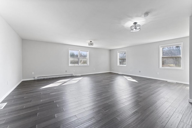 empty room featuring a baseboard heating unit, baseboards, and dark wood-type flooring