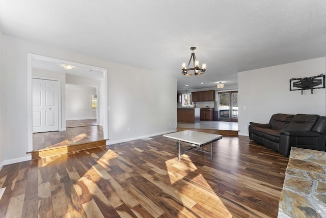 living room with baseboards, an inviting chandelier, and wood finished floors