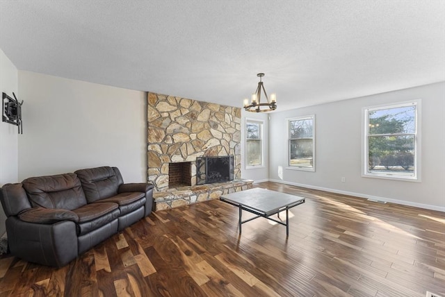 living room featuring a wealth of natural light, a stone fireplace, and wood finished floors