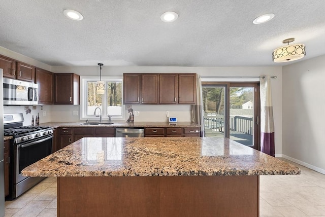 kitchen with a sink, plenty of natural light, appliances with stainless steel finishes, and light stone countertops