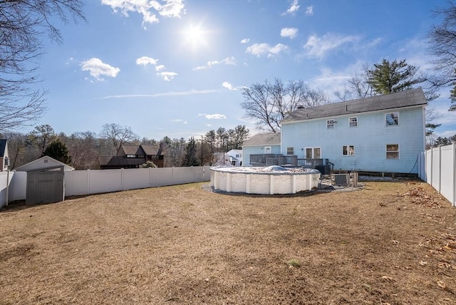 view of yard with an outbuilding, a fenced backyard, a shed, cooling unit, and a fenced in pool