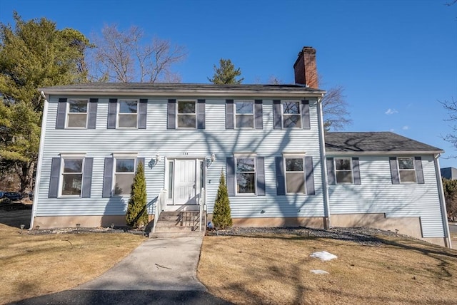 colonial-style house with a front lawn and a chimney