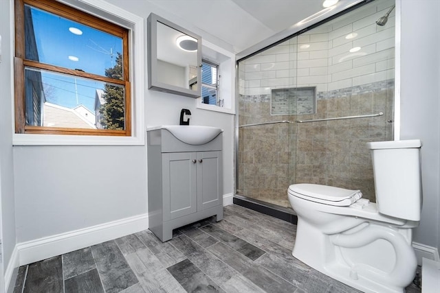 bathroom with a stall shower, baseboards, toilet, wood tiled floor, and vanity