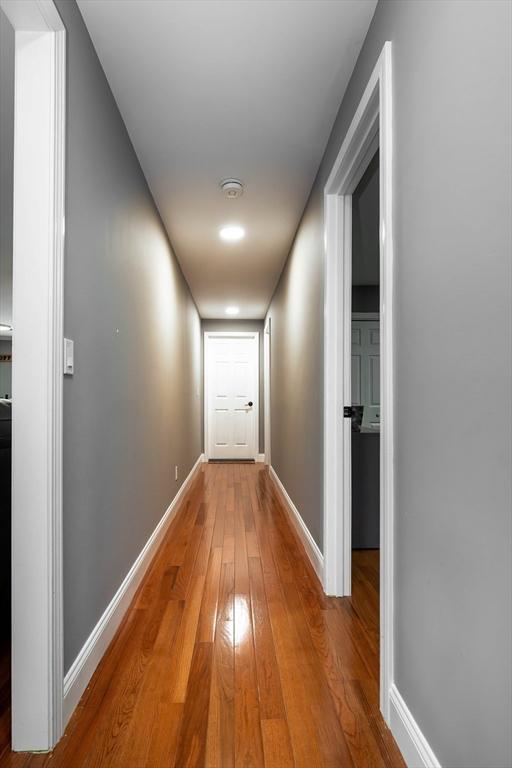 hallway featuring hardwood / wood-style flooring and baseboards