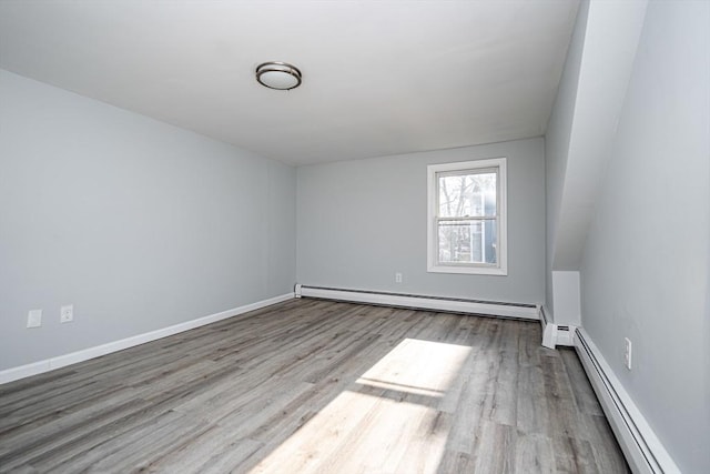 interior space with baseboards, a baseboard heating unit, and wood finished floors