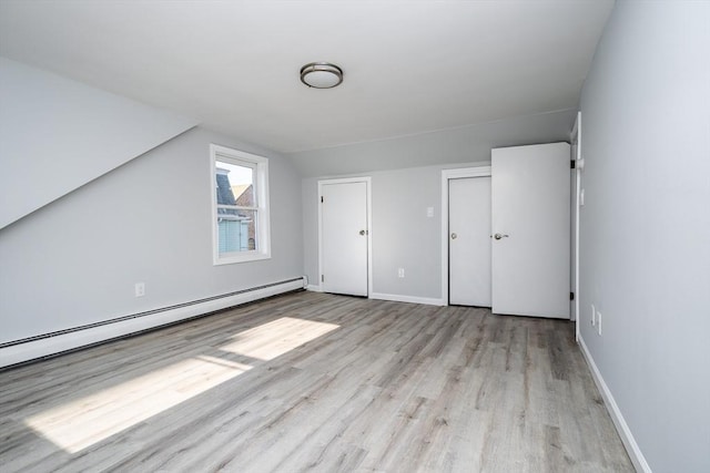 bonus room featuring a baseboard heating unit, light wood-type flooring, vaulted ceiling, and baseboards