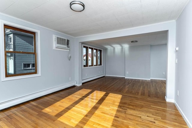 unfurnished room featuring a wall unit AC, a baseboard heating unit, wood finished floors, ornamental molding, and baseboard heating