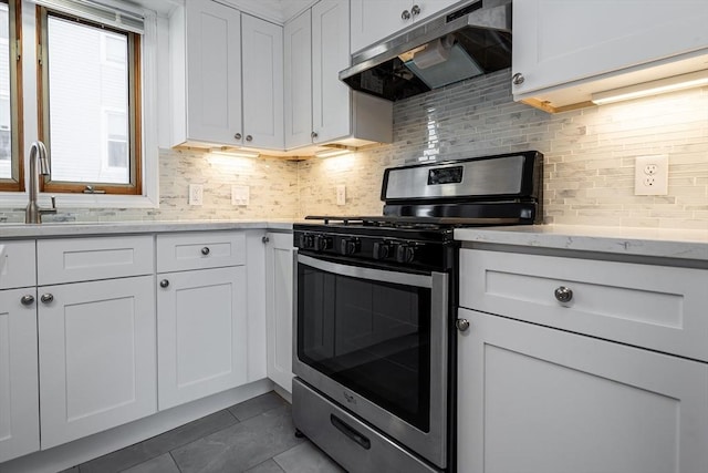 kitchen featuring tasteful backsplash, stainless steel gas stove, a sink, white cabinetry, and under cabinet range hood