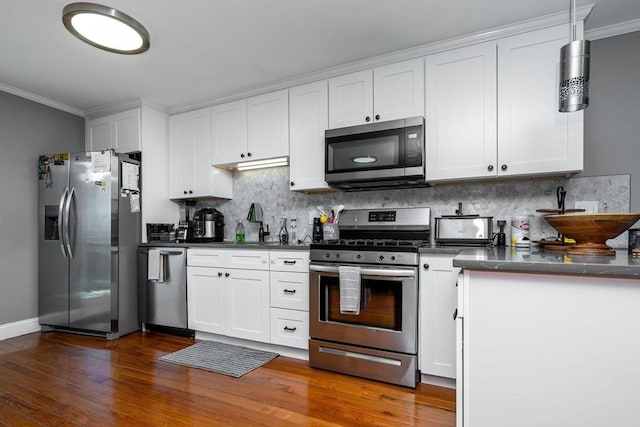 kitchen featuring dark countertops, stainless steel appliances, crown molding, and wood finished floors