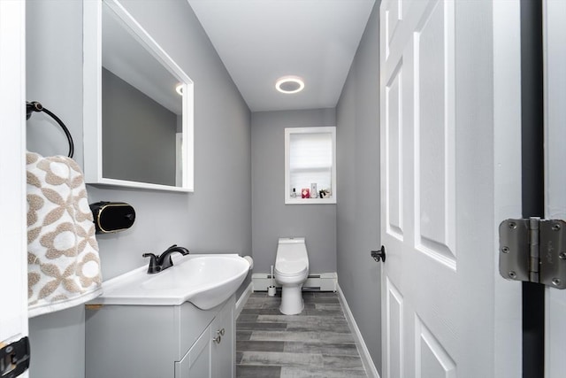 bathroom featuring toilet, wood finished floors, vanity, baseboards, and baseboard heating