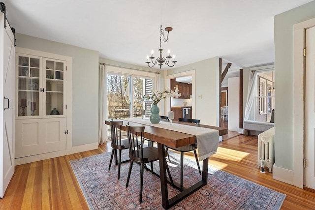 dining room with a notable chandelier, radiator heating unit, and light wood-type flooring