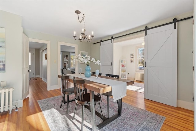 dining area featuring a barn door, light wood-style flooring, and radiator