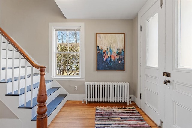 foyer with radiator, stairs, and light wood-type flooring