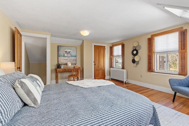 bedroom with baseboards, radiator, and wood finished floors