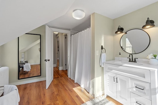 full bath featuring curtained shower, vanity, wood finished floors, and radiator heating unit