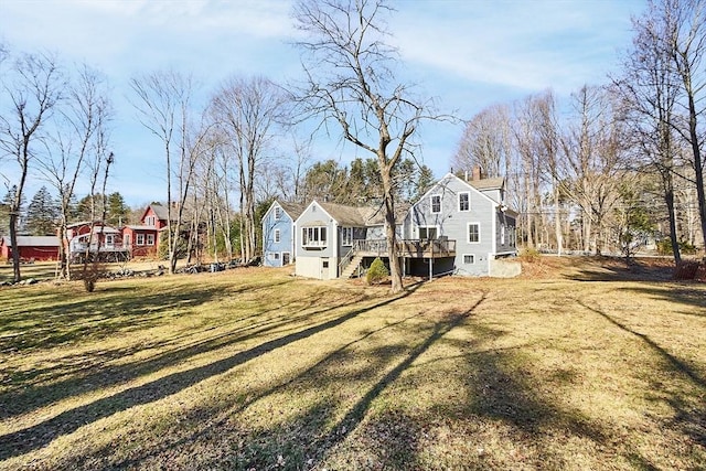 back of property with a wooden deck, a yard, and stairs