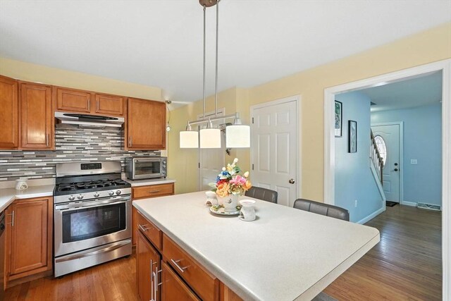 82 Lloyd Ave, Springfield, MA 01119 - kitchen featuring gas range, under cabinet range hood, brown cabinetry, tasteful backsplash, and a center island