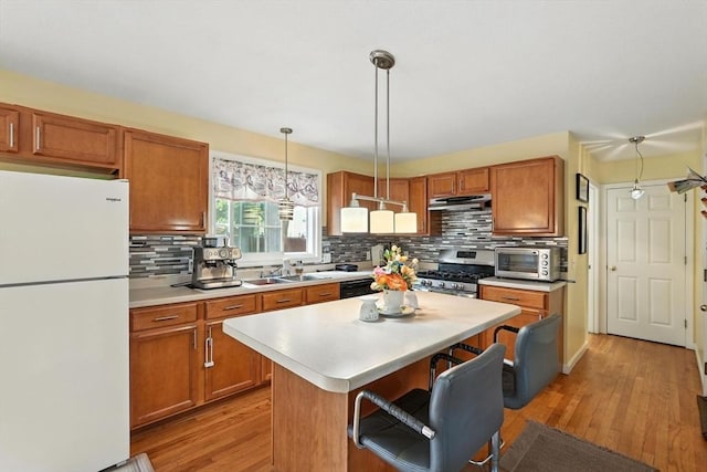 82 Lloyd Ave, Springfield, MA 01119 - kitchen with freestanding refrigerator, under cabinet range hood, stainless steel gas stove, light countertops, and decorative backsplash