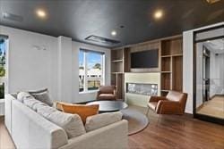 home theater room featuring recessed lighting, built in features, wood finished floors, and a fireplace
