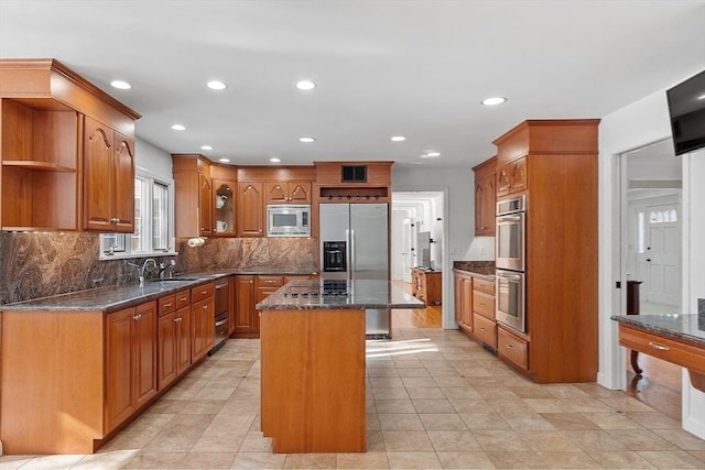 kitchen featuring brown cabinetry, a kitchen island, appliances with stainless steel finishes, and open shelves