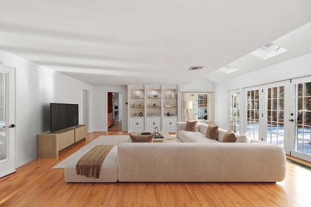 living area with light wood-type flooring, lofted ceiling with skylight, visible vents, and french doors