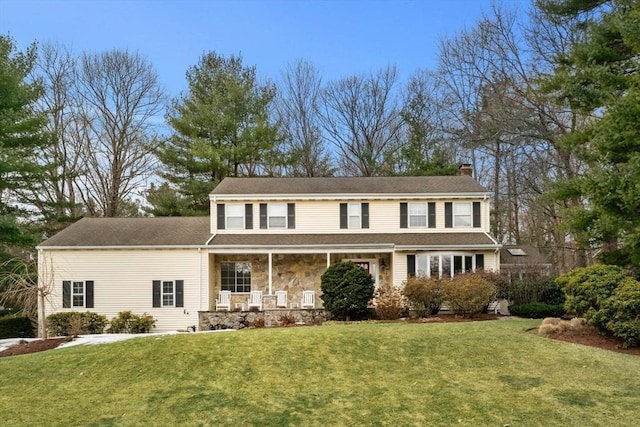 view of front of property featuring covered porch, stone siding, a chimney, and a front yard