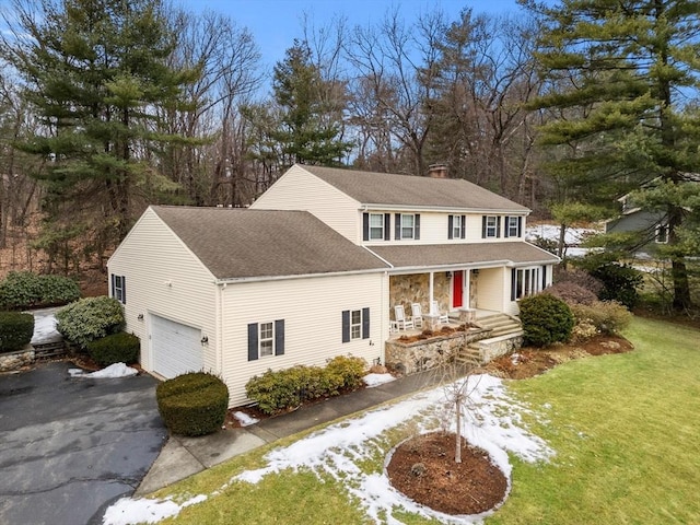 view of front of home featuring aphalt driveway, a shingled roof, a chimney, and a front lawn