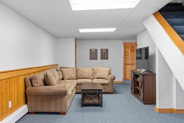 living area featuring a drop ceiling, a baseboard radiator, carpet flooring, and wooden walls