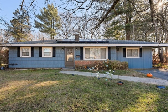 single story home featuring solar panels and a front lawn