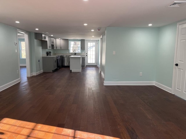 kitchen with appliances with stainless steel finishes, a center island, sink, and dark wood-type flooring