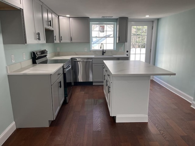 kitchen featuring sink, a kitchen island, dark wood-type flooring, and appliances with stainless steel finishes