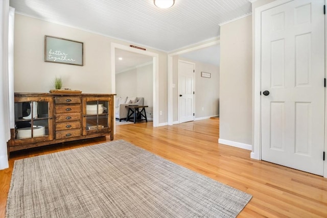 interior space with baseboards, ornamental molding, and light wood finished floors