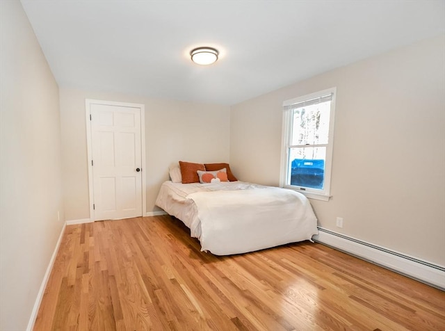 bedroom featuring light wood-type flooring, baseboards, and a baseboard heating unit