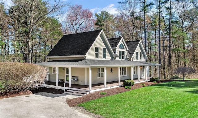 farmhouse with covered porch, a shingled roof, and a front yard