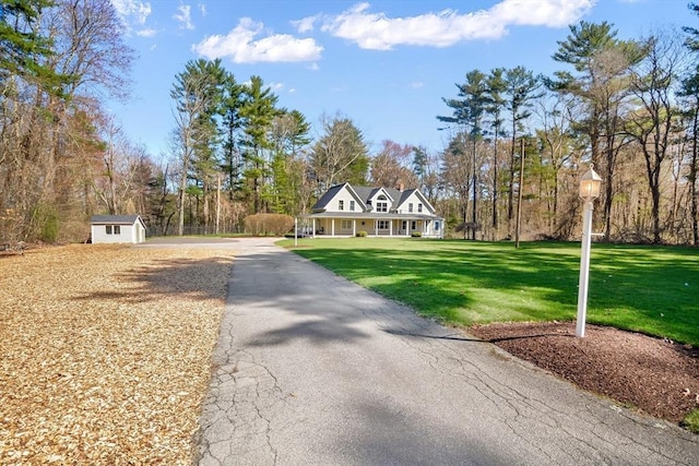 view of front of property featuring an outdoor structure, a shed, a front yard, and aphalt driveway