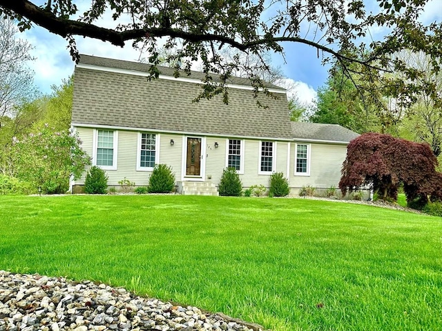 view of front of home with roof with shingles, a front yard, and entry steps