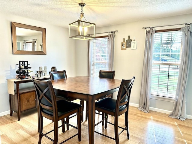 dining space with light wood-style flooring, baseboards, and a textured ceiling
