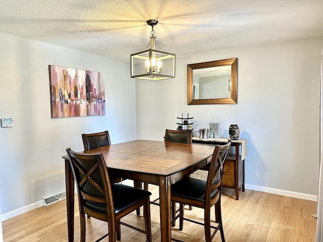 dining area featuring light wood-style flooring, a chandelier, and baseboards