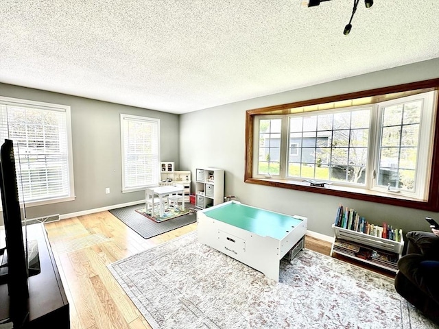 game room with wood finished floors, a textured ceiling, and baseboards