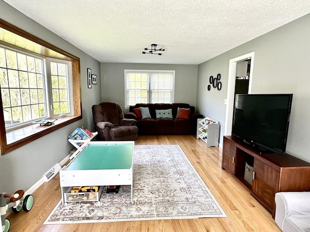 living area featuring light wood-type flooring, a textured ceiling, and baseboards