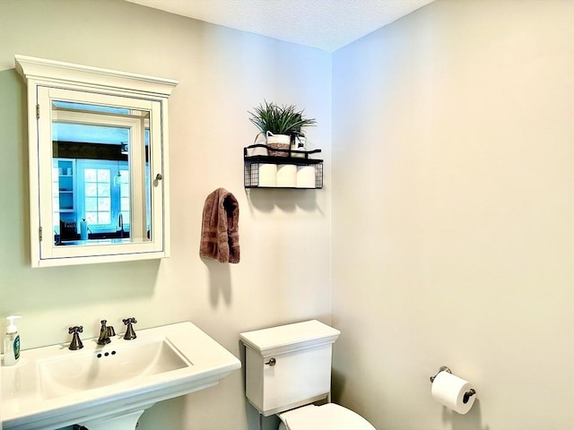 bathroom with toilet, a sink, and a textured ceiling