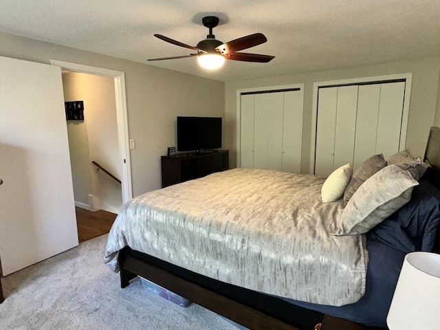 bedroom featuring multiple closets, carpet, ceiling fan, and a textured ceiling