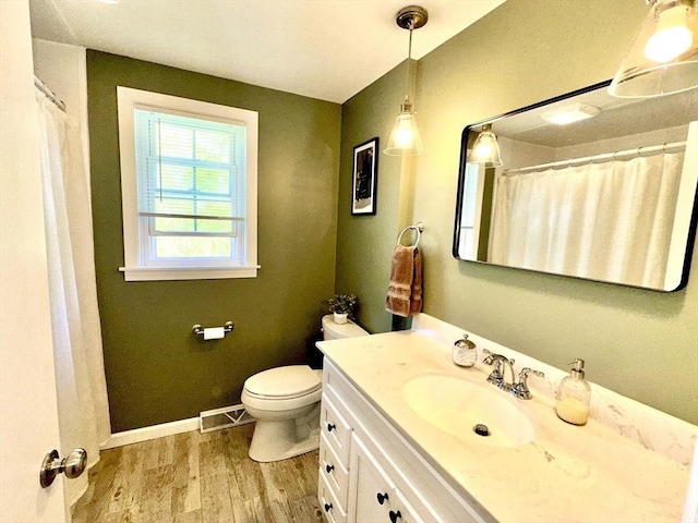 bathroom with wood finished floors, vanity, toilet, baseboards, and curtained shower